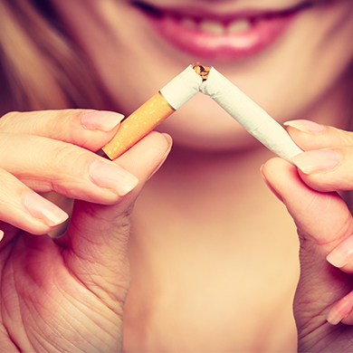 Junge Frau hält zerbrochene Zigarette in den Händen: Mit dem Rauchen aufzuhören, unterstützt gesunde Viskosität des Blutes.
