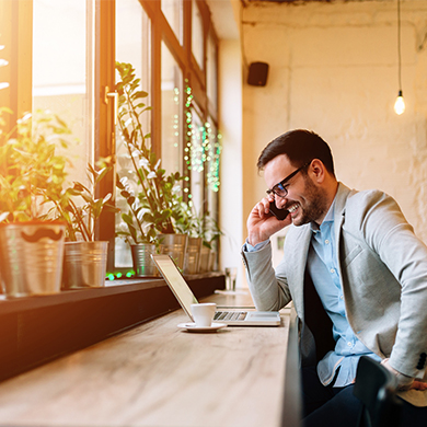 Businessman sitzt vor seinem Laptop und telefoniert dabei.